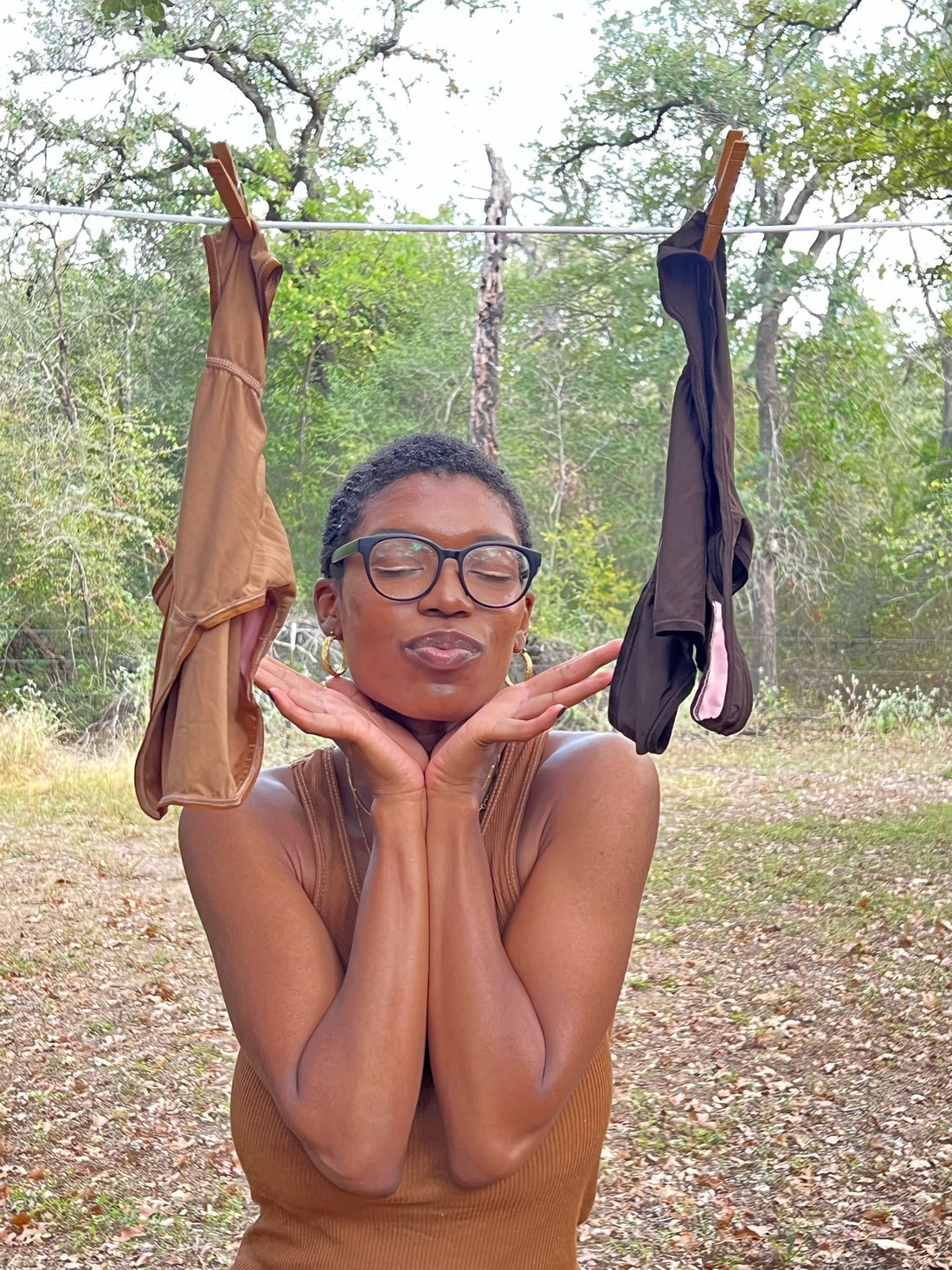 Woman standing between two pairs of skin-tone inclusive underwear by FOR THE FEW Intimates